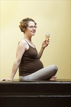 Caucasian pregnant woman eating ice cream cone