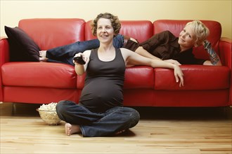 Caucasian pregnant lesbian couple watching TV