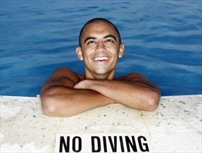 Mixed race man smiling at edge of swimming pool