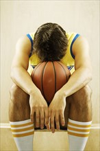 Frustrated Caucasian basketball player sitting on sidelines