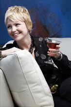 Caucasian woman drinking wine on sofa