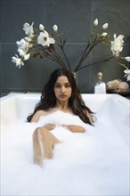 Hispanic woman relaxing in bubble bath