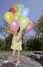 Mixed race girl carrying colorful balloons in park