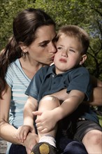 Mixed race mother kissing hurt son in park