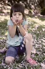 Mixed race girl playing with flowers in park