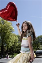 Caucasian girl holding heart-shape balloon