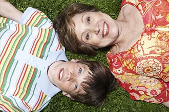 Senior Caucasian woman and grandson laying in grass