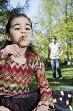 Caucasian girl blowing bubbles in park