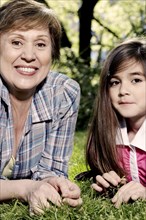 Senior Caucasian woman and granddaughter laying in grass