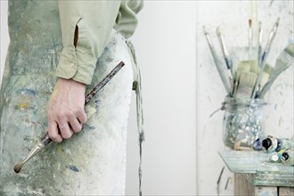 Caucasian artist holding paintbrush in studio