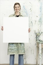 Caucasian painter holding blank canvas in studio