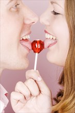 Caucasian couple licking lollipop