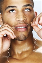 Mixed race man flossing his teeth