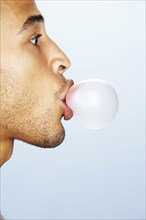 Mixed race man blowing bubble with gum