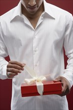 Mixed race man opening wrapped gift