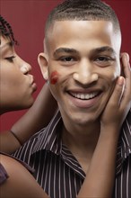 Woman leaving lipstick kiss on boyfriend's cheek