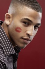 Mixed race man with lipstick kiss on cheek