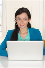 Mixed race businesswoman working at laptop