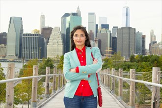 Mixed race woman on footbridge in front of city skyline