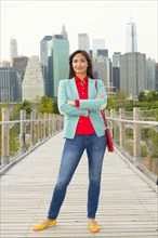 Mixed race woman on footbridge in front of city skyline