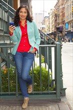 Mixed race woman using cell phone in city