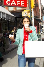 Mixed race woman drinking cup of coffee in city