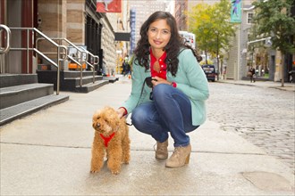 Mixed race woman walking dog on urban sidewalk