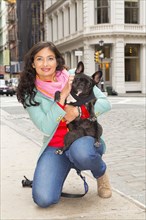Mixed race woman holding dog on urban sidewalk