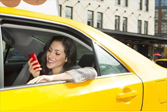 Mixed race woman using cell phone in taxi