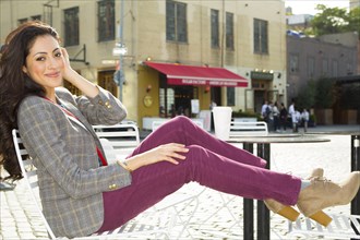 Mixed race woman sitting at urban sidewalk cafe