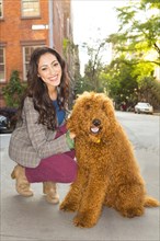 Mixed race woman petting dog on city street