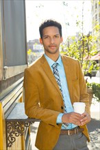 Mixed race businessman having cup of coffee