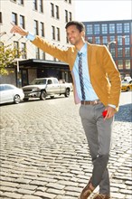 Mixed race businessman hailing taxi on city street