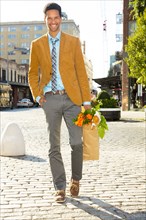 Mixed race businessman carrying flowers on city street