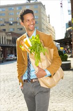Mixed race businessman with groceries on city street