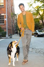 Mixed race man walking dog on city street