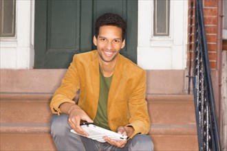 Mixed race man sitting on front steps