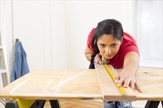Mixed race woman measuring plank of wood