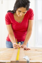 Mixed race woman measuring plank of wood