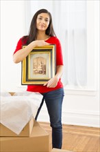 Mixed race woman unpacking cardboard boxes