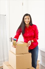 Mixed race woman packing cardboard boxes