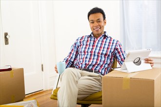Mixed race man having cup of coffee in new home