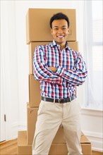 Mixed race man standing by cardboard boxes in new home