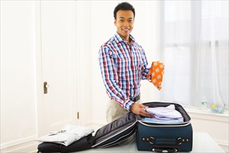 Mixed race businessman packing suitcase