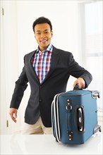 Mixed race businessman carrying suitcase