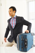 Mixed race businessman carrying suitcase