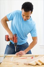 Mixed race carpenter using power drill