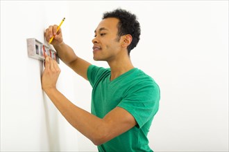 Mixed race man using level on wall