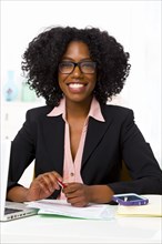 Mixed race businesswoman smiling at desk