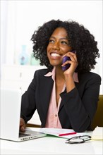 Mixed race businesswoman talking at cell phone at desk